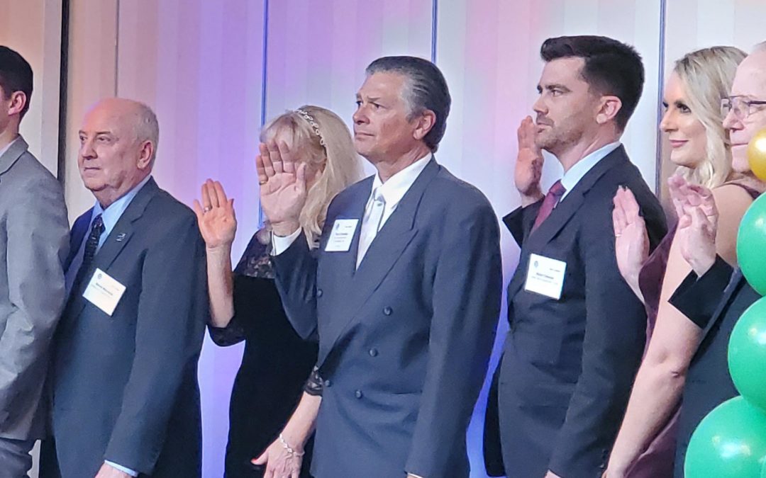 Photo of a group of men and women with hands raised swearing in as board of directors