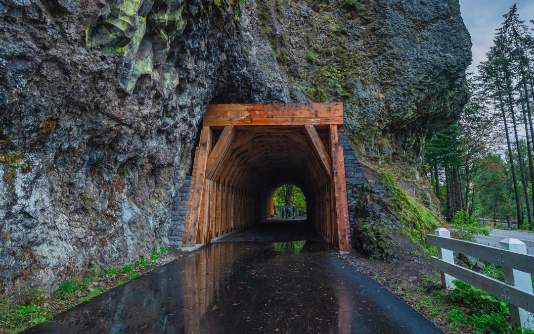 Wooden tunnel running through a cliff with white fence on the right