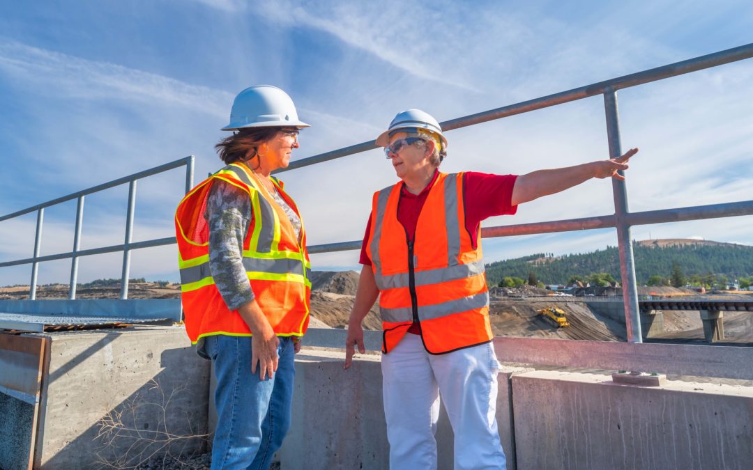 Two women wearing hard hats and high visibility vests standing on a construction site