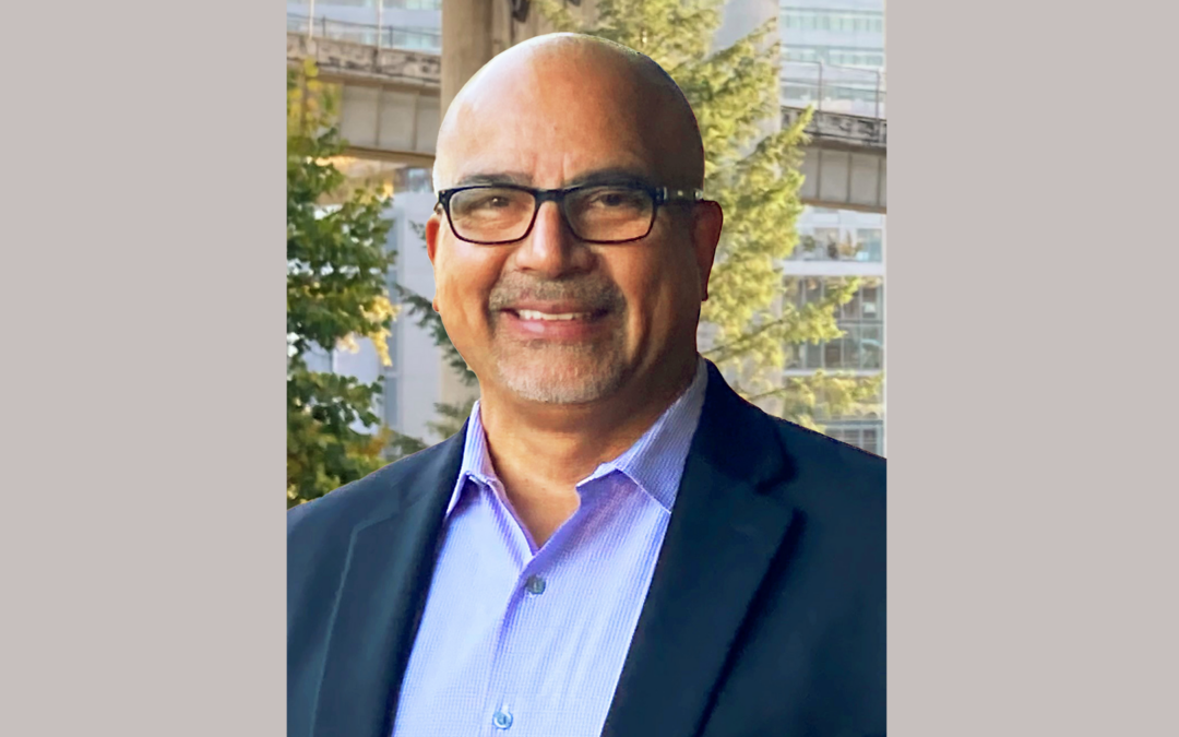 Headshot of man in blue collared shirt and blue blazer